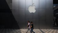 This photo taken on August 3, 2017 shows people walking past an Apple store in Beijing. AFP / Greg Baker