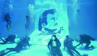 Divers instal Tamim Al Majd billboard underwater at the Aquatic Center of Qatar University Sports Activities Department.