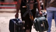 A rebel fighter carries suitcases and his weapon prior to boarding a bus as rebel fighters the besieged Waer district in the central Syrian city of Homs, May 21, 2017. (REUTERS / Omar Sanadiki) 