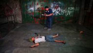 FILE PHOTO: An investigator takes notes next to the body of a man killed in a shoot-out with police in Manila,  October 21 2016