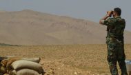 A Syrian pro-government forces uses binoculars in the western Qalamoun, on August 20, 2017, during an offensive against Islaimc State (IS) group fighters. Lebanon's battle against IS comes as the jihadist group faces assaults in both neighbouring Syria an