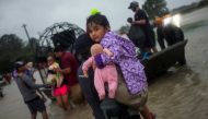 A woman holds a girl as her family arrives to high ground by boat due to floods caused by Tropical Storm Harvey along Tidwell Road in east Houston, Texas, U.S. August 28, 2017. REUTERS/Adrees Latif.