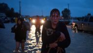 A woman holds her dog as she arrives to high ground after evacuating her home due to floods caused by Tropical Storm Harvey along Tidwell Road in east Houston, Texas, U.S. August 28, 2017. REUTERS/Adrees Latif