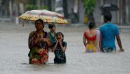 Indians wade through a flooded street during heavy rain showers in Mumbai on August 29, 2017.  AFP / Punit Paranjpe