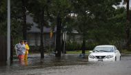 People walk past an abandoned car after the area was inundated with flooding from Hurricane Harvey on August 29, 2017 in Houston, Texas. / AFP.