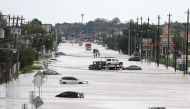 A car gets towed while men walk in the flooded waters of Telephone Rd. in Houston, Texas on August 30, 2017. Monster storm Harvey made landfall again Wednesday in Louisiana, evoking painful memories of Hurricane Katrina's deadly strike 12 years ago, as ti