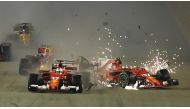 The car of Ferrari's Finnish driver Kimi Raikkonen (R) is seen after a crash as Ferrari's German driver Sebastian Vettel (C) leads during the Formula One Singapore Grand Prix in Singapore on September 17, 2017. / AFP / MANAN VATSYAYANA
