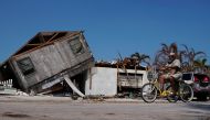 A man rides his trike past a destroyed house following Hurricane Irma in Big Pine Key, Florida, U.S., September 19, 2017. REUTERS/Carlo Allegri
