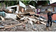 A man and a dog walk amid the rubble after Tropical Storm Nate struck the Los Anonos neighborhood in San Jose, Costa Rica. Photo: AFP.