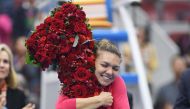 Simona Halep of Romania celebrates after being presented with a bouquet in the shape of the number '1', after taking the top ranking by winning her women's singles semi-final match against Jelena Ostapenko of Latvia at the China Open tennis tournament in 