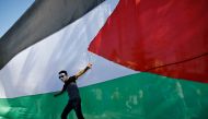 A Palestinian youth poses in front of his national flag during celebrations in Gaza City after rival Palestinian factions Hamas and Fatah reached an agreement on ending a decade-long split following talks mediated by Egypt on October 12, 2017.  AFP / Moha