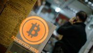 This file picture taken on February 28, 2014 shows a man talking on a mobile phone in a shop displaying a bitcoin sign during the opening ceremony of the first bitcoin retail shop in Hong Kong (AFP / Philippe Lo) 