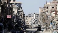 FILE PHOTO: A fighter of Syrian Democratic Forces stands amidst the ruins of buildings near the Clock Square in Raqqa, Syria October 18, 2017. REUTERS/Erik De Castro/File photo
