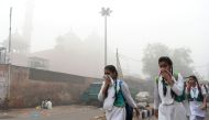Indian schoolchildren cover their faces as they walk to school amid heavy smog in New Delhi on November 8, 2017. / AFP / SAJJAD HUSSAIN