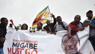 People wave a Zimbabwean national flag and carry banners during a demonstration demanding the resignation of Zimbabwe's president on November 18, 2017 in Harare.  AFP 
