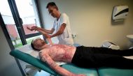 Franck, 33-year-old who had suffered burns over 95 percent of his body and was saved by a skin transplant from his identical twin Eric, in a world-first operation, receives a physiotherapy session by French physiotherapist Christophe Loisel, at the rehabi