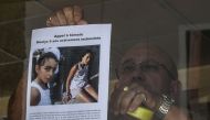 This file photo taken on August 28, 2017 shows the owner of a bar attaching an appeal for witnesses poster issued by the Gendarmerie of Pont-de-Beauvoisin for Maelys, a 9-year-old girl, who disappeared during a wedding party on August 26 overnight. AFP / 