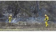 Firefighters water down burning embers from an overnight fire in Fillmore, California on December 15, 2017, as the Thomas Fire flared up again, growing to 252,500 acres and becoming the fourth largest fire in California's history. / AFP.
