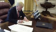 United States President Donald J. Trump signs a document during an event to sign the Tax Cut and Reform Bill in the Oval Office at The White House in Washington, DC on December 22, 2017. (AFP / Brendan SMIALOWSKI)