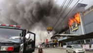This photo was taken on December 23, 2017, shows a firefighter standing in front of a burning shopping mall in Davao City on the southern Philippine island of Mindanao.  AFP / MANMAN DEJETO
