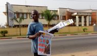 A Liberian newspaper vendor walks in fromt of The National Elections Commission in Monrovia on December 28, 2017.  AFP / SEYLLOU
