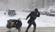 A mail delivery person pulls her cart through the snow on January 4, 2018 in Brooklyn, New York. AFP / Angela Weiss