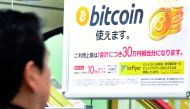 A man walks past a poster that informs customers that bitcoin can be used in this shop in Tokyo on January 06, 2018. Bitcoin is recognised as legal tender in the world's third-biggest economy and nearly one third of global bitcoin transactions in December