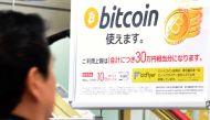 A man walks past a poster that informs customers that bitcoin can be used in this shop in Tokyo on January 06, 2018. / AFP / Toru YAMANAKA 