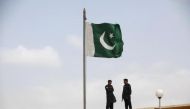  File photo of Pakistani flag flies on a mast as paramilitary Frontier Corps soldiers talk, August 23, 2013. REUTERS/Akhtar Soomro/Files 