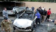 People inspect a damaged car in Sidon, southern Lebanon, January 14, 2018. REUTERS/Ali Hashisho
