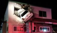 A car dangles off the second floor of a building after speeding into a median and going airborne, according to local media, in Santa Ana, California, U.S., January 14, 2018, in this picture obtained from social media. OCFA PIO/via REUTERS