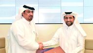 QU President, Dr Hassan Al Derham, and QLC Deputy Manager Director and Director of Administration and Finance, Dr Ali Jassim Al Kubaisi, exchanging documents during the signing ceremony.