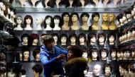 File photo of a vendor, helps put on a wig on a customer at a wig shop near the central train station in Shanghai, China January 18, 2017. REUTERS/Aly Song/File Photo