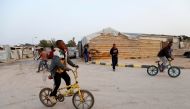 Libyan boys displaced from the town of Tawergha ride bicycles at a camp in Tripoli, Libya, February 5, 2018.  Reuters/Ismail Zitouny