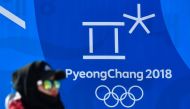 A woman passes past a logo of the the Pyeongchang 2018 Winter olympic Games and the rings, two days prior to the Pyeongchang 2018 Winter olympic Games at the Phoenix Park venue in Pyeongchang on February 6, 2018. / AFP / LOIC VENANCE
