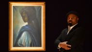 Nigerian author Ben Okri poses with a work of art by Nigerian painter and sculptor Ben Enwonwu entitled 'Tutu' expected to realise 200,000-300,000 GBP (278000-417,000 USD) at auction in Bonhams auction house London on February 7, 2018.  AFP / Ben Stansall