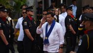This photo taken on February 6, 2018 shows Philippine President Rodrigo Duterte (C) saluting as he arrives to attend the Bureau of Customs anniversary in Manila.  AFP / Ted Aljibe