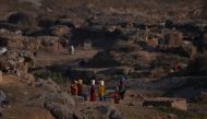 File photo of Afghan refugee women hold water cans on their heads on their way to on their mud houses at a refugee camp in Islamabad, January 19, 2018. / AFP / AAMIR QURESHI /