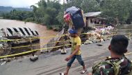 A resident carries belongings over a bridge damaged by flooding following heavy rains brought by tropical Storm Sanba in the town of Jaboanga in Agusan del Norte province on the southern island of Mindanao on February 13, 2018.  AFP / Erwin MASCARINAS
