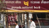 File photo of Indian men walking past signage for the state-owned Punjab National Bank (PNB) in Mumbai on February 14, 2018. / AFP / INDRANIL MUKHERJEE 
