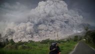 An Indonesian man takes picture of Mount Sinabung volcano as it spews thick volcanic ash into the air in Karo, North Sumatra, on February 19, 2018. AFP / Endro Rusharyanto 
