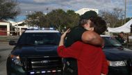 Chris Grady a senior at Marjory Stoneman Douglas High School hugs Broward County Sheriff officer Brad Griesinger as he guards the front gate of the school on February 18, 2018 in Parkland, Florida. Joe Raedle/Getty Images/AFP 