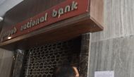 A man reads a notice by the Indian Central Bureau of Investigation (CBI) stating that the Brady House branch of the Punjab National Bank (PNB) has been sealed next to the entrance of the branch in Mumbai on February 19, 2018.  AFP / INDRANIL MUKHERJEE
