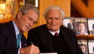 Former US President George W. Bush (L) signs a copy of his new book 