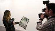 A journalist holds a photograph, part of the art-installation by Spanish artist Santiago Sierra 'Political prisoners of contemporary Spain' as she informs on its removal from ARCO art fair in Madrid on February 21, 2018. AFP / Gabriel Bouys