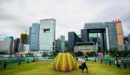 Visitors look at Japanese artist Yahoo Kusama's 'pumpkin: big, 2008' at the Harbour Arts Sculpture Park in Hong Kong on February 22, 2018.  AFP / Anthony Wallace