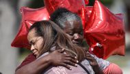 Kay Blake (L) hugs school bus driver Pearlie Corker as they visit in front of Marjory Stoneman Douglas High School as teachers and staff are allowed to return to the school for the first time since the mass shooting on campus on February 23, 2018 in Parkl