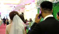 File photo of Huong (L) and Quan (R) enter the hall for their wedding party in Hanoi, January 23, 2018. / AFP / Nhac Nguyen 