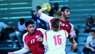 A Qatari player prepares to shoot while a Serbian player attempts to spoil his effort during their placement match  played at the Ali bin Hamad Al Attiyah Stadium in Al Sadd.  Qatar won 24-23.
