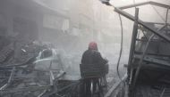 A Syrian walks with his bicycle amid debris of buildings after Assad Regime's airstrike hit residential areas in Eastern Ghouta's Douma town despite decisions to implement a ceasefire made separately by Russia and the UN Security Council, in Damascus, Syr
